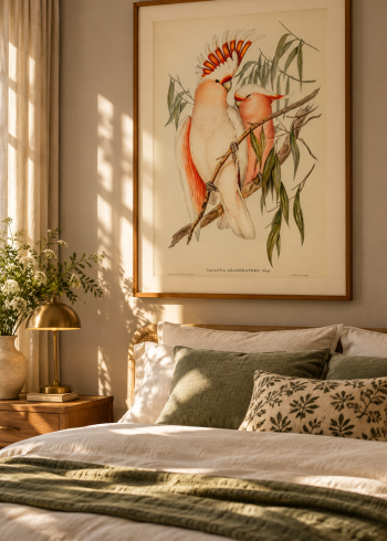Tableau encadré du puzzle Les Cacatoès accroché au-dessus d'une tête de lit en rotin dans une chambre lumineuse.